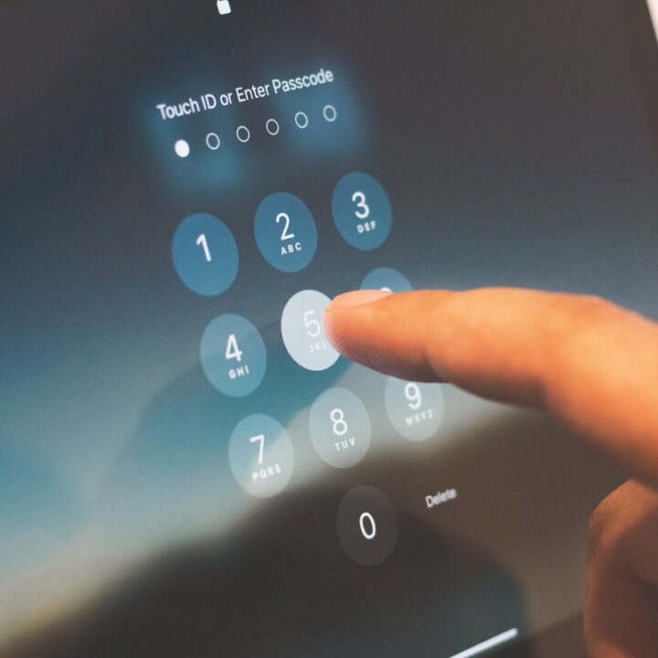 Finger entering a passcode on a tablet lock screen