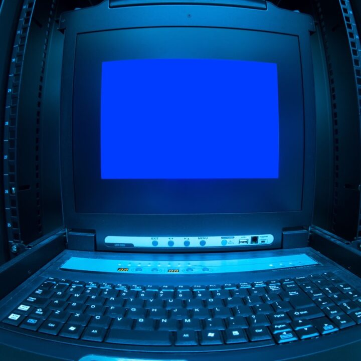 Blue computer terminal screen and keyboard in a server rack
