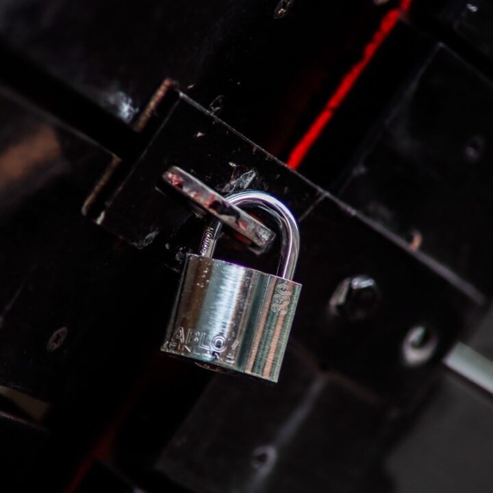 Metal padlock securing a dark door latch