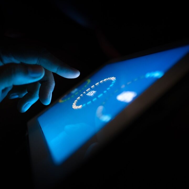 Finger interacting with a glowing touchscreen interface