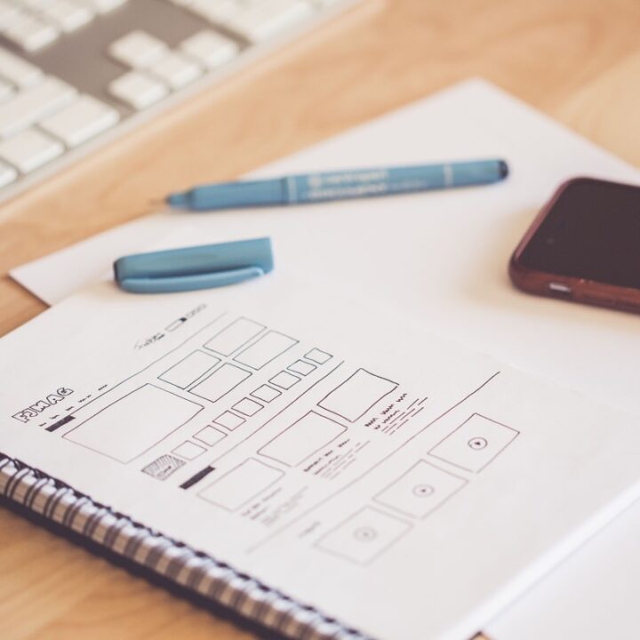 Website wireframe sketched in a notebook beside a keyboard