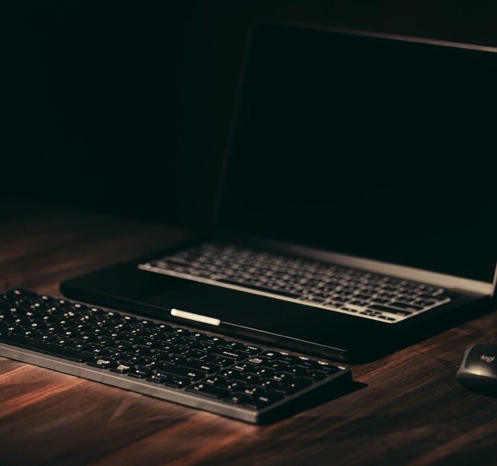 Dark workspace with a laptop and wireless keyboard