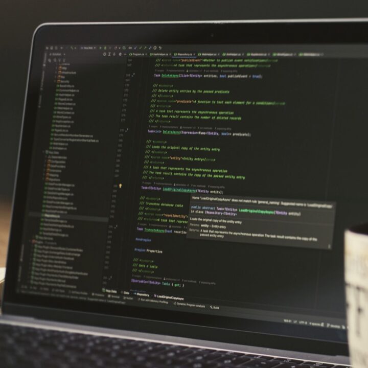 Laptop displaying code in a dimly lit workspace